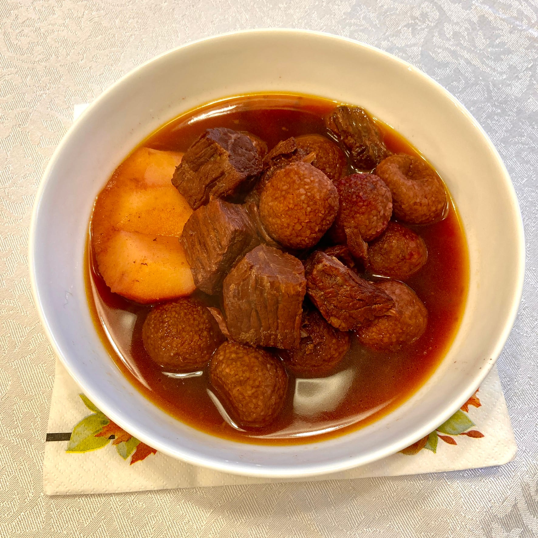 A dish of kibbeh safarjaliyeh, meatballs cooked with quince in a dark sauce.