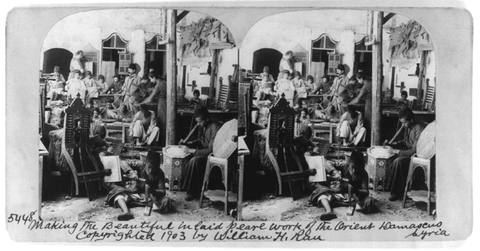 A historical photograph of craftsmen seated at low benches making mother-of-pearl inlay in Damascus.