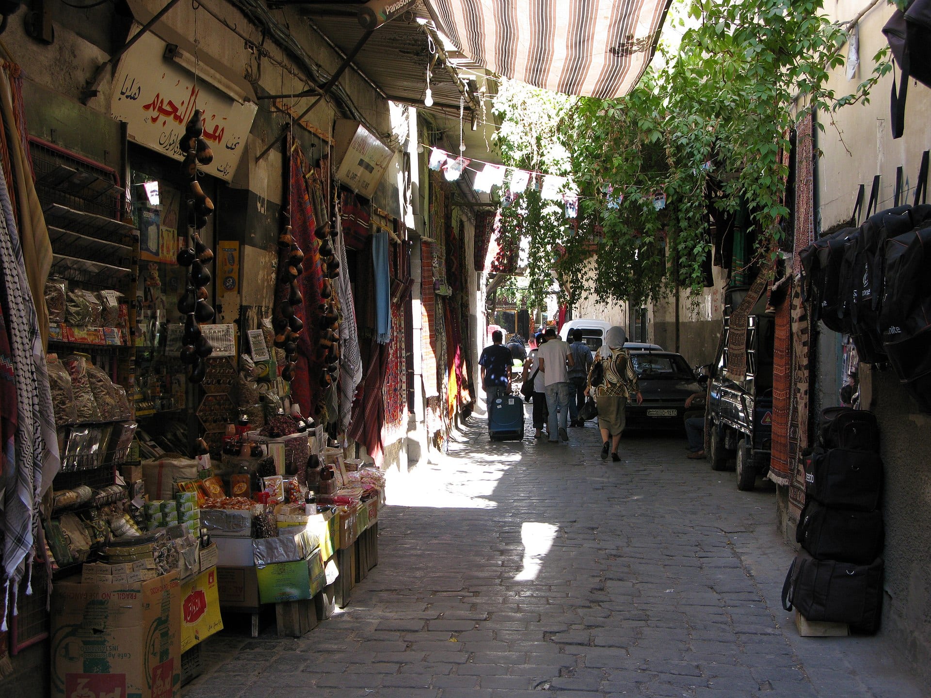 A covered souq in Damascus, goods stacked along both sides of the passage.