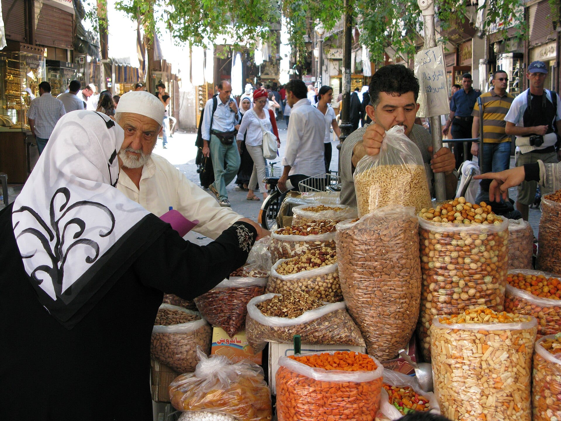 A street market in Damascus, produce laid out on tables under awnings.